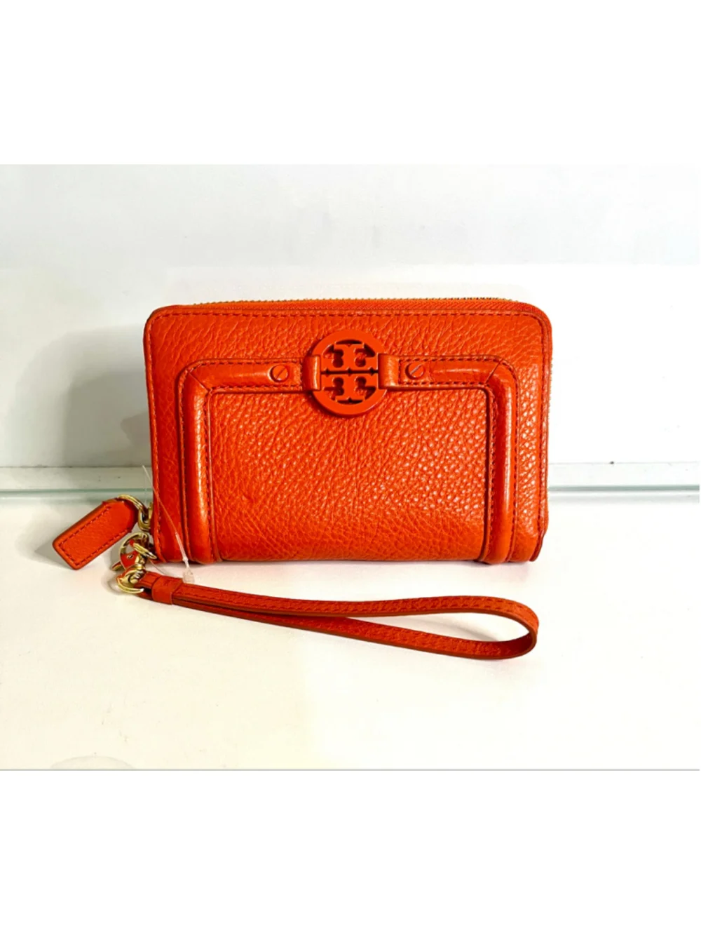 Tory Burch Amanda zip-around wallet featuring vibrant orange pebbled leather.